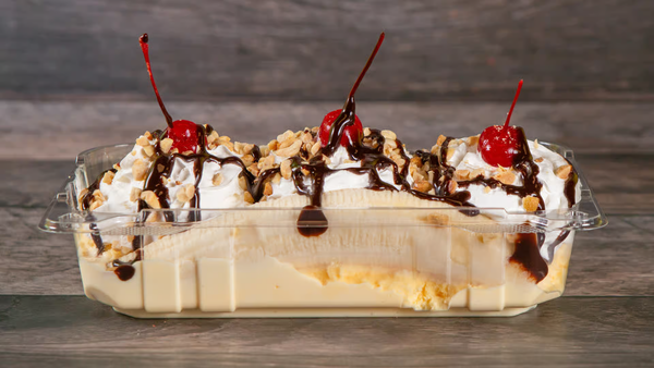 Bananas topped with three scoops of ice cream, fresh berries, nuts, and whipped cream.